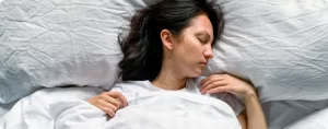 אישה ישנה במיטה על מצאים לבנים - שמנים אתריים לשינה